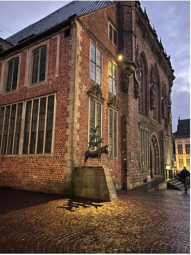 Photograph of a brick building in Bremen with a statue of an animal in front and ornate windows 